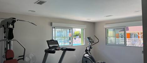 A gym with exercise equipment, large windows, and a view of the outside.