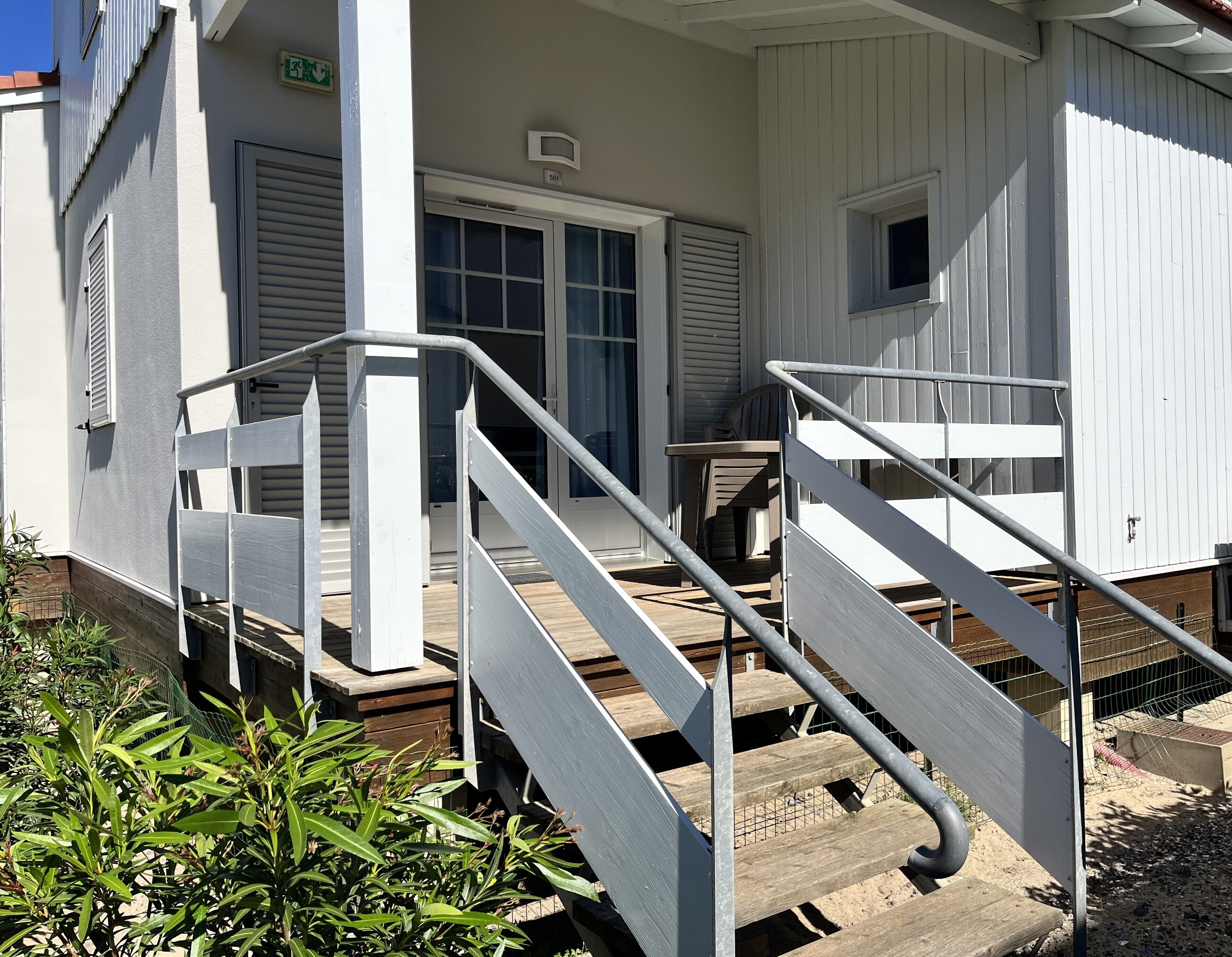 A building with a porch, a set of stairs with metal railings, and a door with a number above it.