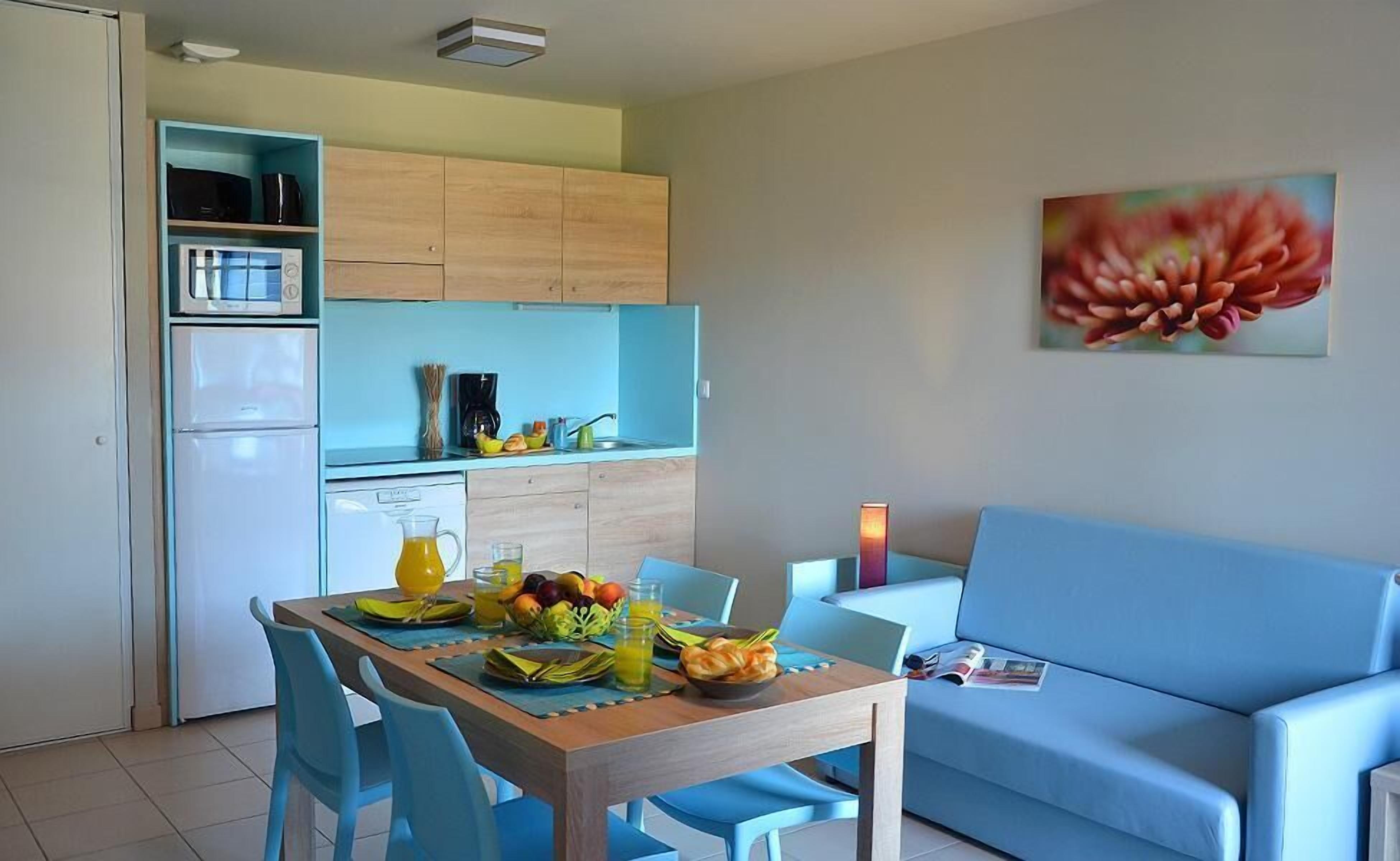 A compact living space with a dining area, kitchenette, and a sofa.