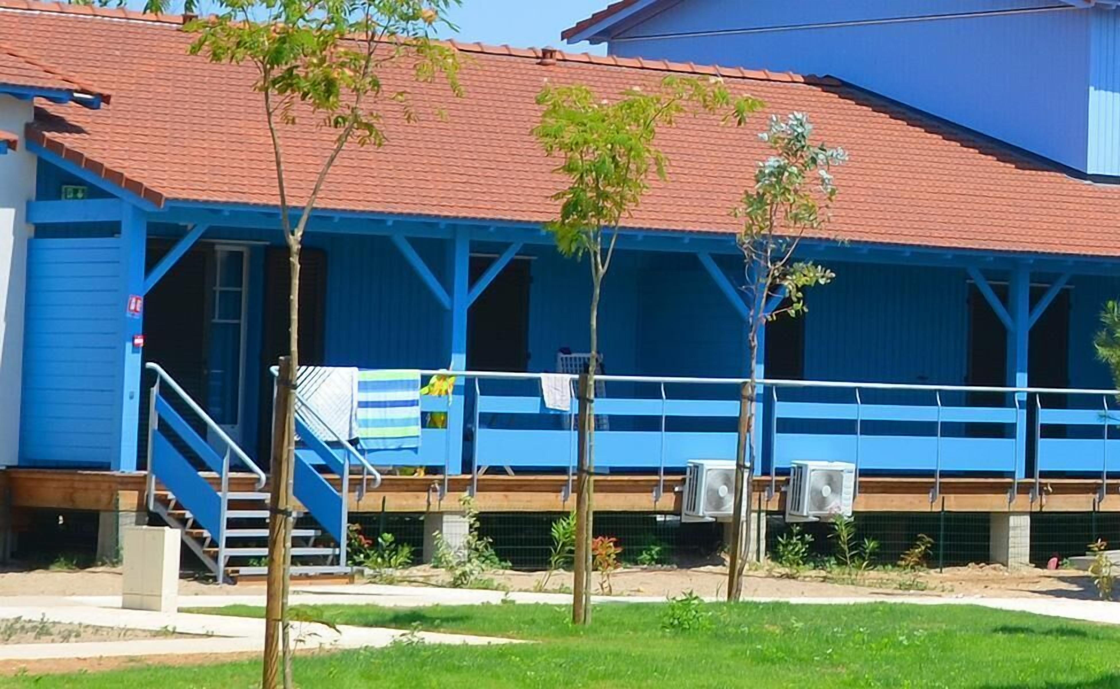 Un edificio blu con tetto rosso, un'area esterna coperta con scale e condizionatori.