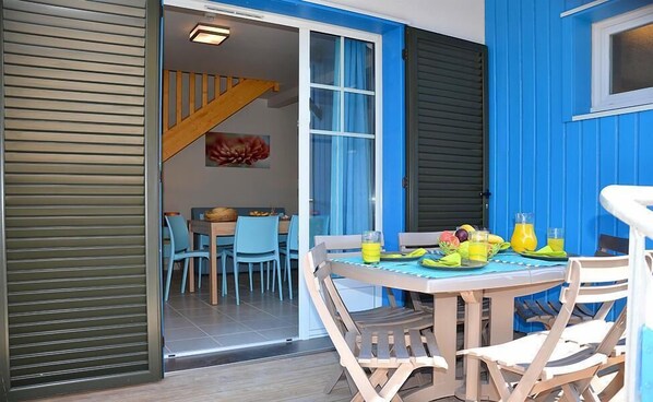A dining area with a table set for two, a staircase, and a view into the dining room.