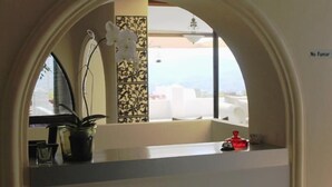 A hotel reception area with a view of the cityscape through a large arched window. - Hotel Boutique Valverde Cumbres de la Escalon (San Salvador)