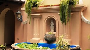 A courtyard with a fountain, a statue, and hanging plants. - Hotel Boutique Valverde Cumbres de la Escalon (San Salvador)