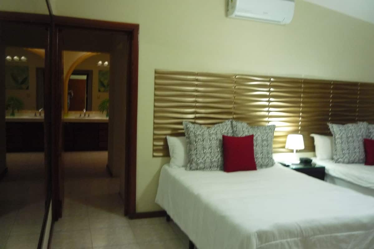A hotel room with a bed, a nightstand, and a mirror.