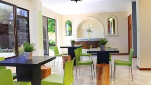 A modern dining area with green chairs and a black table, large windows, and potted plants. - Hotel Boutique Valverde Cumbres de la Escalon (San Salvador)