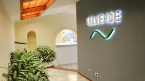 A hallway with a sign reading "ALVERDE" and a green logo, potted plants, and arched doorways. - Hotel Boutique Valverde Cumbres de la Escalon (San Salvador)