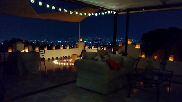 A rooftop terrace with a sofa and chairs, string lights, and candles. - Hotel Boutique Valverde Cumbres de la Escalon (San Salvador)