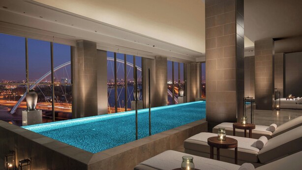 A rooftop infinity pool with a city view, lounge area with seating, and ambient lighting. - The St. Regis Astana (Astana)