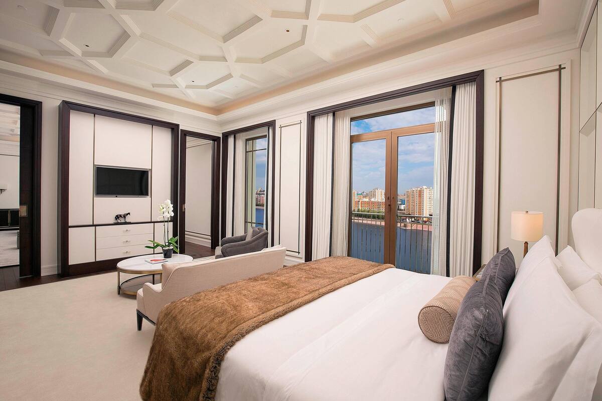 Ein Hotelzimmer mit einem großen Bett, einem Fernseher, einem Schreibtisch und Blick auf die Stadt.