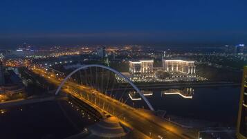 A nighttime cityscape with a prominent bridge and illuminated buildings.