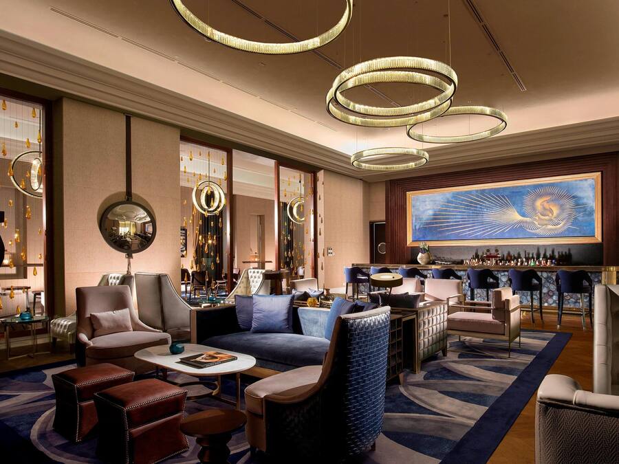 A modern lounge area with sofas, armchairs, and a bar.