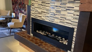 A modern fireplace with a stone mosaic design, a comfortable seating area with a chair, and a flat-screen TV mounted on the wall.