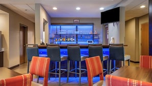 A bar area with a counter, bar stools, and a television screen.