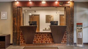 A reception area with wooden accents, a reception desk, a computer, and a hand sanitizer station.