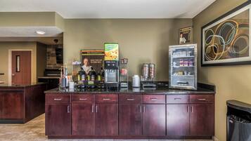 Een kitchenette met een koffiehoek, een koelkast en een prullenbak.