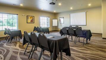 A conference room with a projector, whiteboard, and a large screen.
