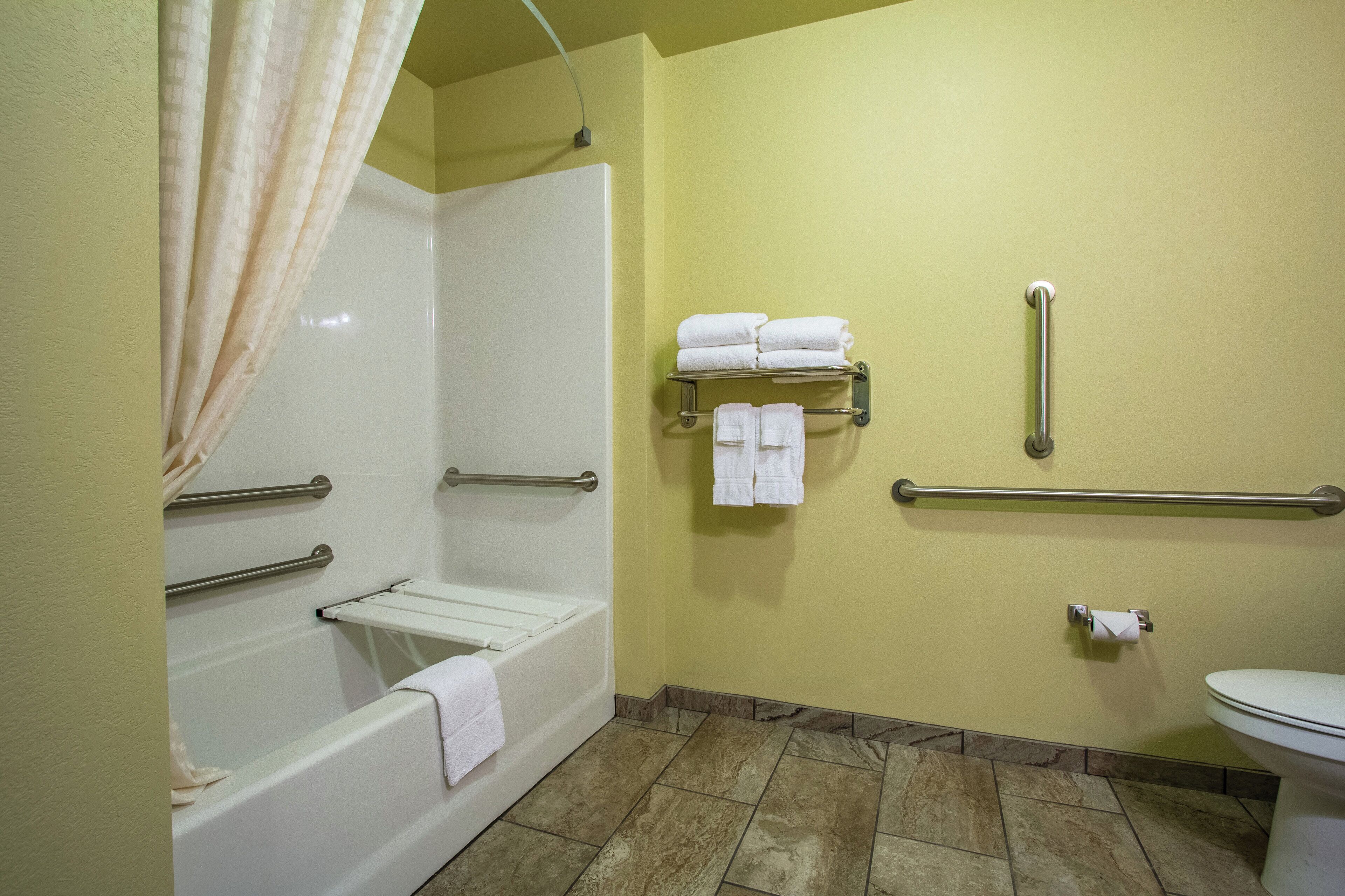 A bathroom with a bathtub, a shower, a toilet, and a towel rack with towels.