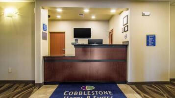 En hotellobby med en receptionsdisk, en platt-TV och en skylt som visar hotellets namn och adress.