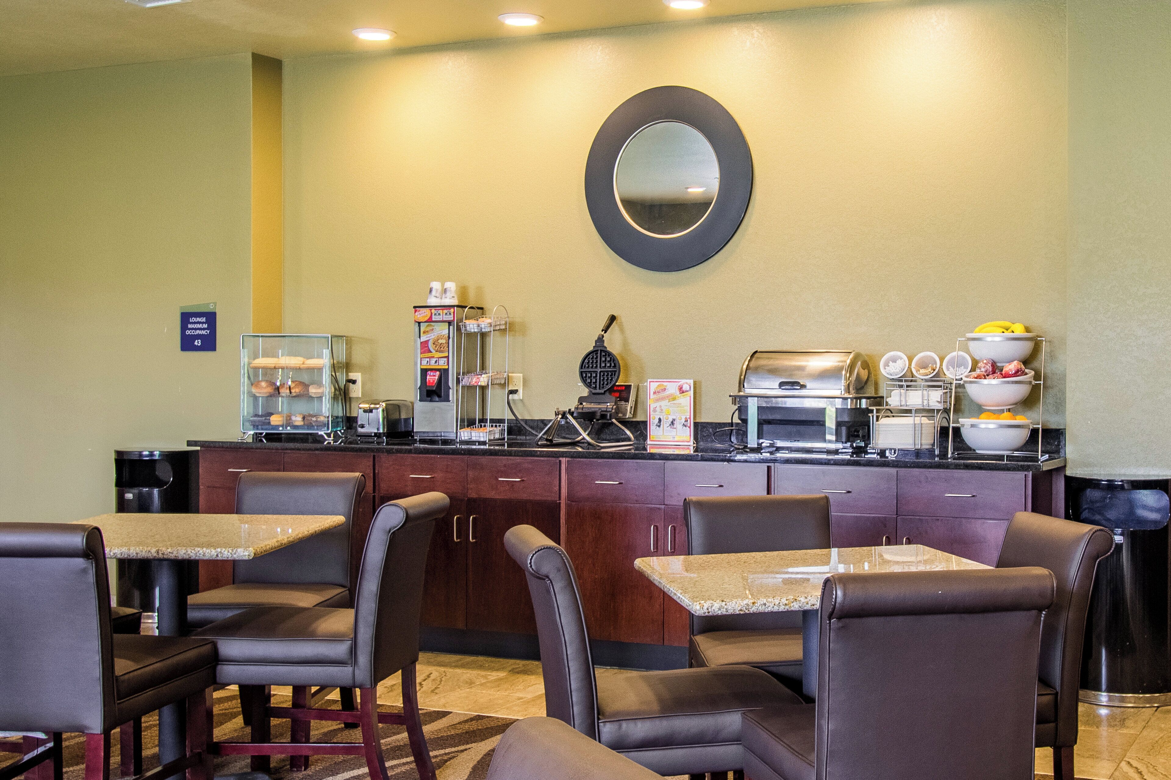 Zona de desayuno de hotel con asientos, una cafetera y un microondas.