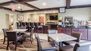 A hotel lobby with a bar area, seating, and a kitchen. - Cobblestone Inn & Suites - Guernsey (Guernsey)