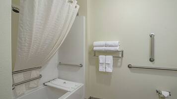 A bathroom with a bathtub, a shower curtain, a towel rack, and a handrail.