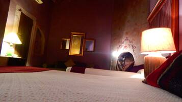 Una habitación de hotel con una cama, dos lámparas, una chimenea y un espejo en la pared.
