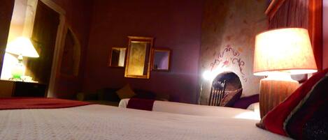 Una habitación de hotel con una cama, dos lámparas, una chimenea y un espejo en la pared.