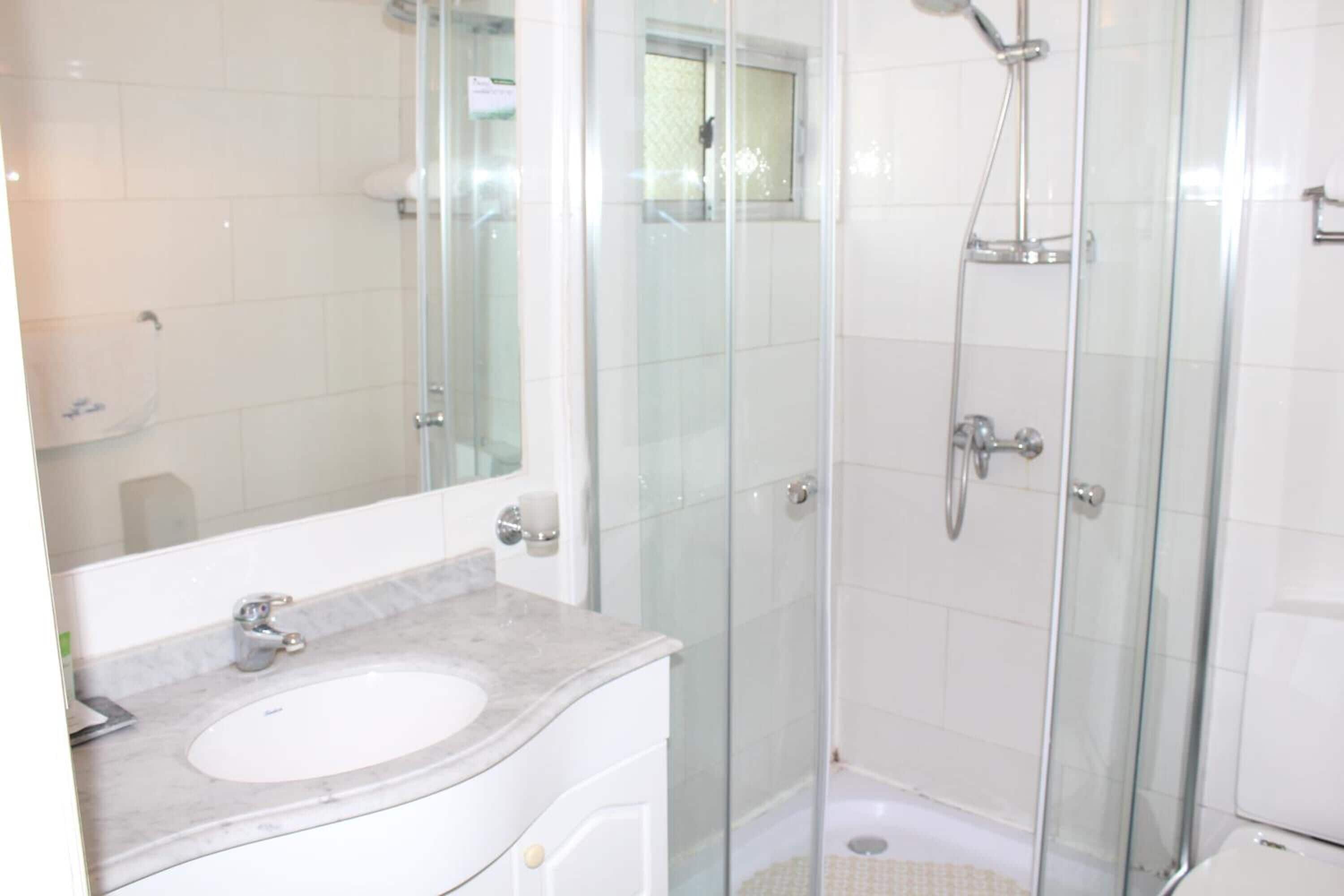 Une salle de bain moderne avec une douche à parois de verre, un lavabo blanc et un grand miroir.