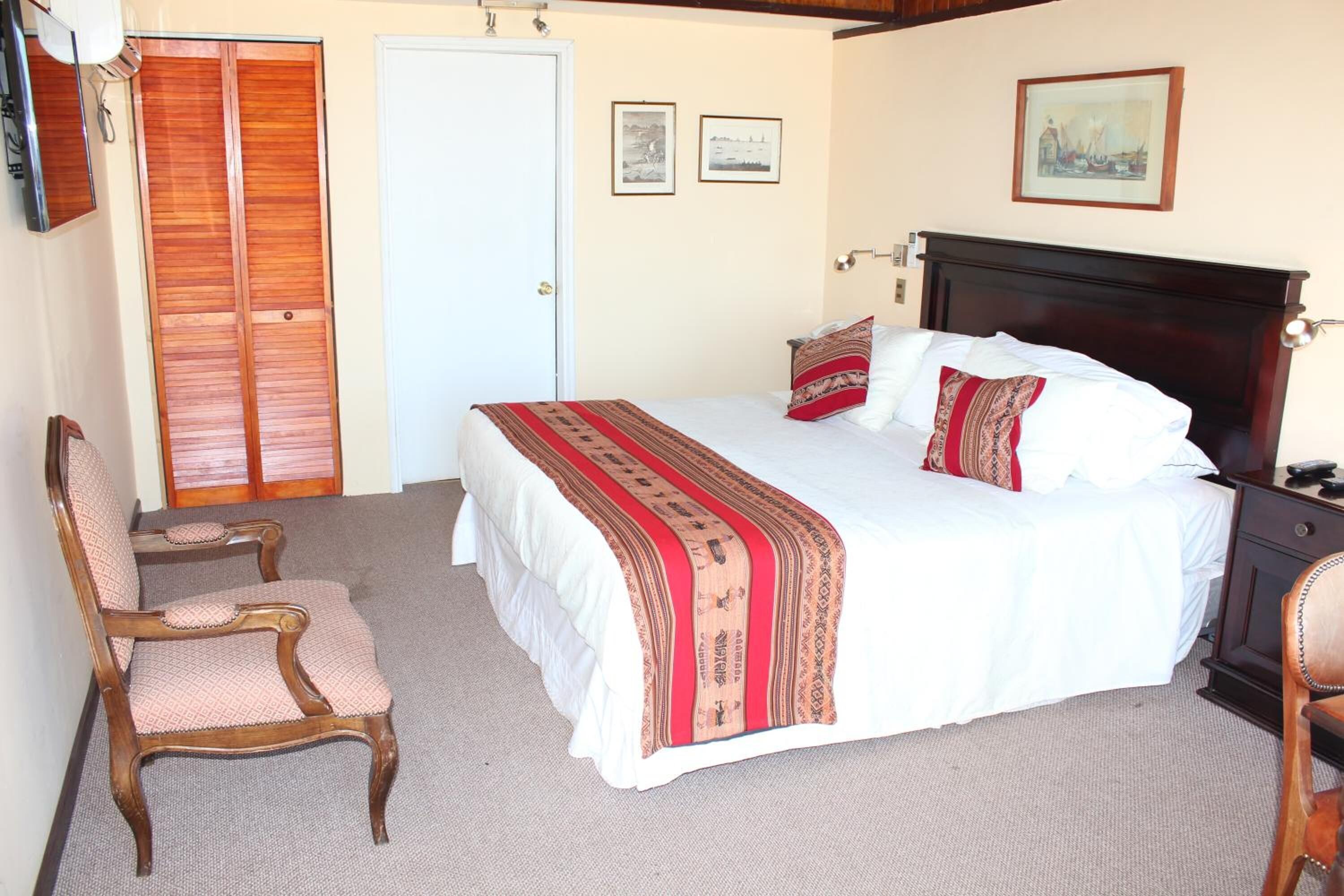Un dormitorio con cama, dos sillas, un armario y una puerta.