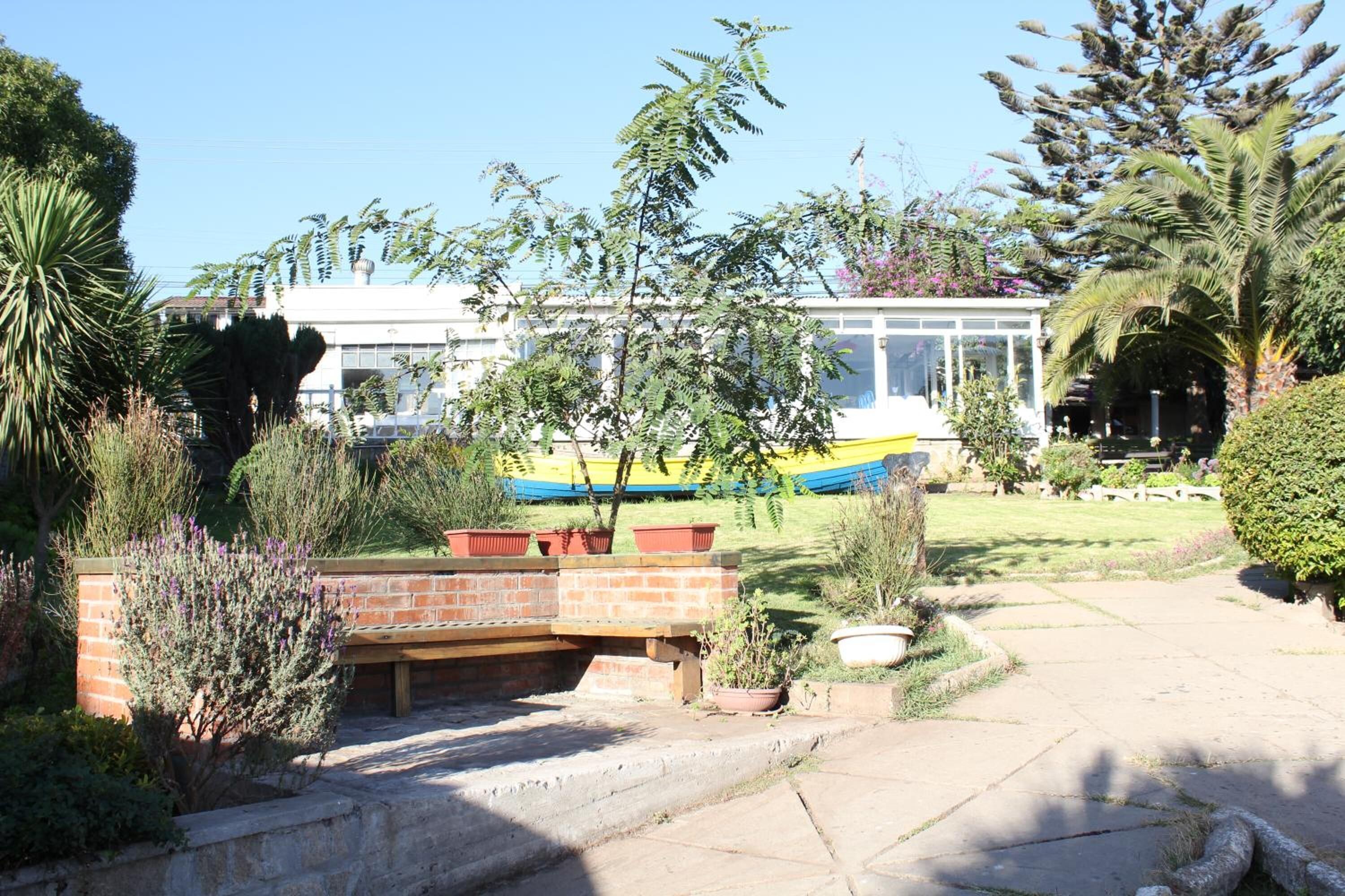 Un jardín con un banco, un pequeño estanque y un edificio al fondo.