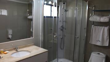 A modern bathroom with a glass-enclosed shower, a sink, and a toilet.