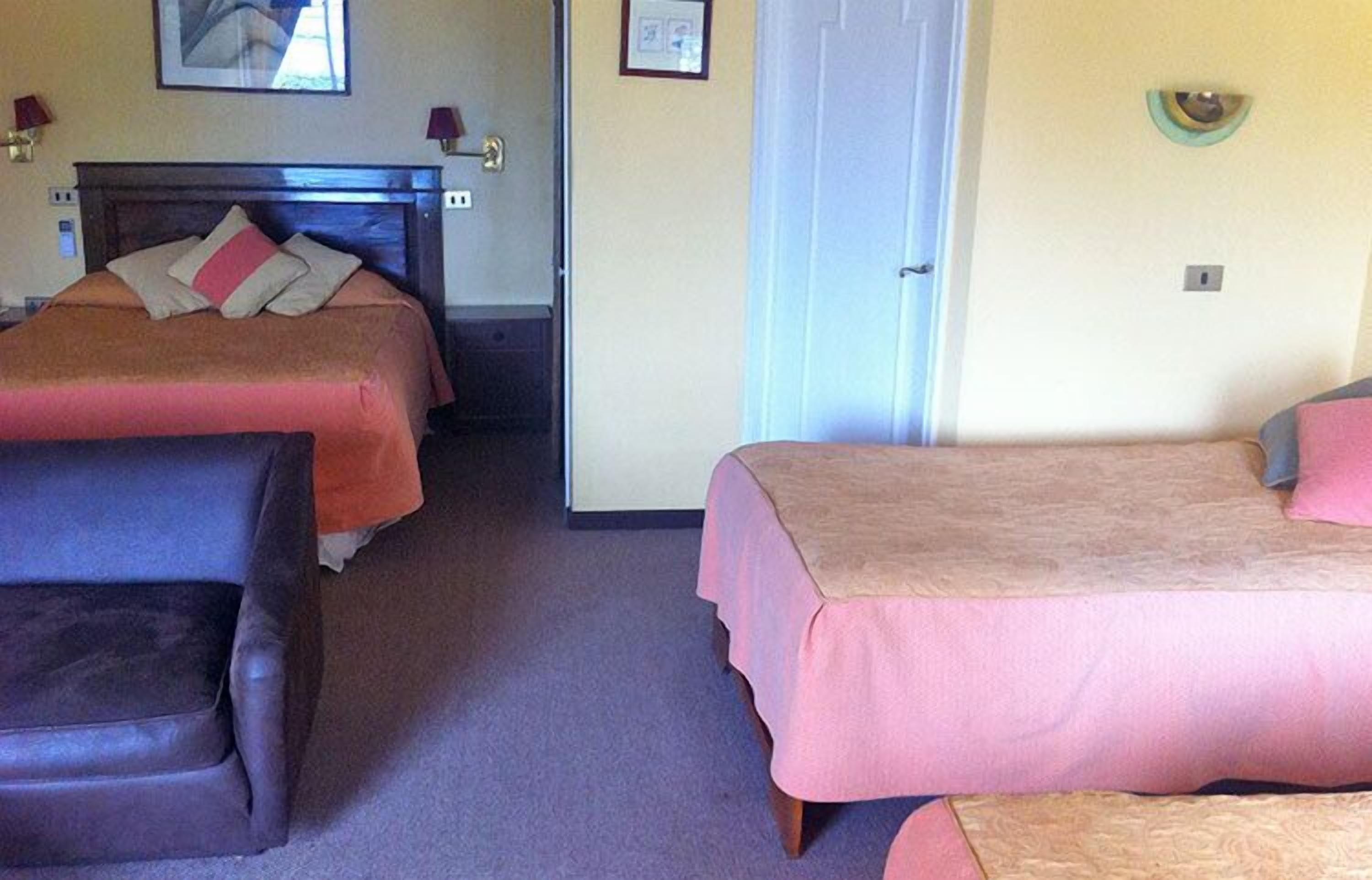 Une chambre d’hôtel avec deux lits, une chaise et une porte.