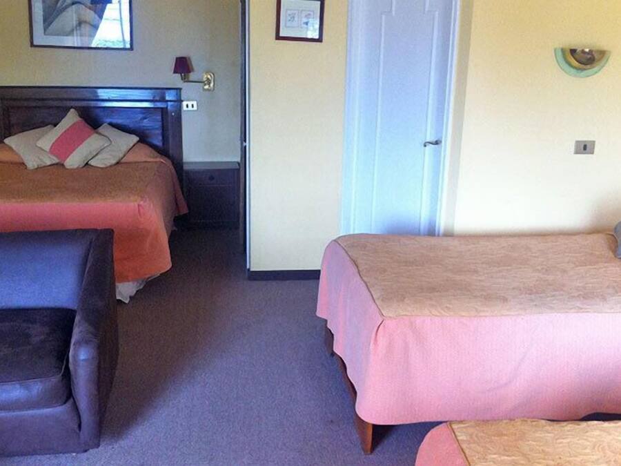 A hotel room with two beds, a chair, and a door.