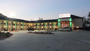 A multi-story hotel with a sign reading "Paris Inn & Suites" and a "NOW OPEN" sign.