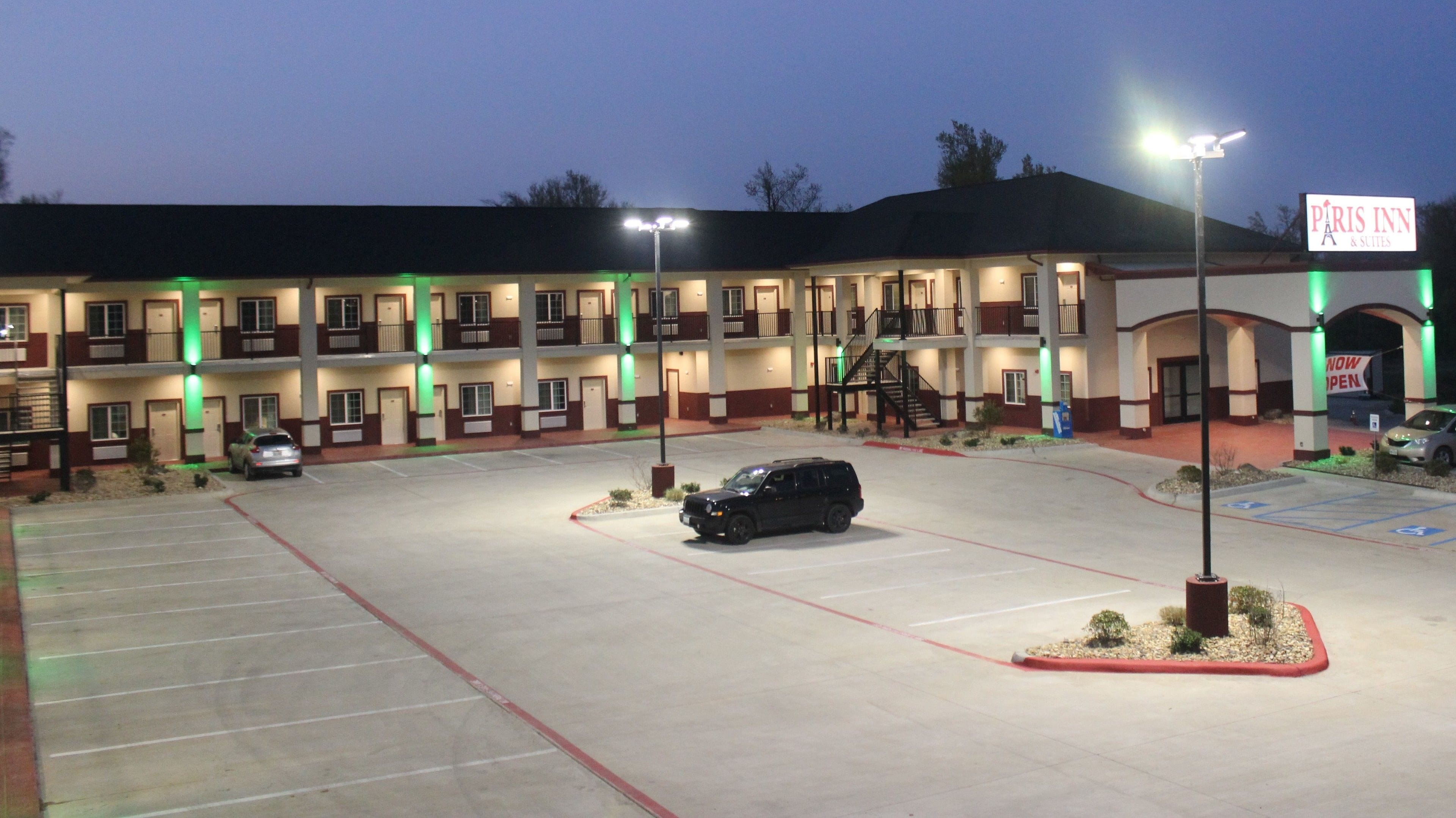 A multi-story hotel with a parking lot, marked handicap spaces, and a sign indicating the hotel is now open.