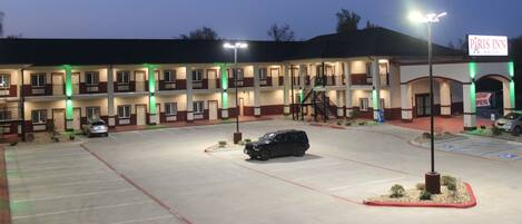 A multi-story hotel with a parking lot, marked handicap spaces, and a sign indicating the hotel is now open.