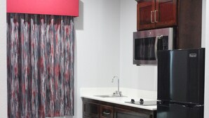 A compact kitchen with a refrigerator, microwave, and wooden cabinets.
