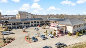 A multi-story hotel with a parking lot and solar panels on the roof.
