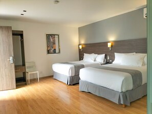 A hotel room with two beds, a wooden floor, a painting on the wall, and a small white table. - El Hotel Business Class – Zamora Centro (Zamora)