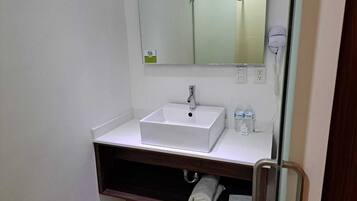 Un bagno con lavandino bianco, uno specchio, un porta asciugamani e una cabina doccia in vetro.