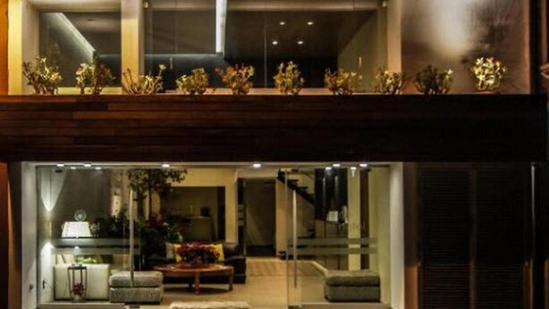 Exterior del hotel Oel, con un diseño moderno, que destaca un llamativo letrero de neón, amplias ventanas y una entrada acogedora.