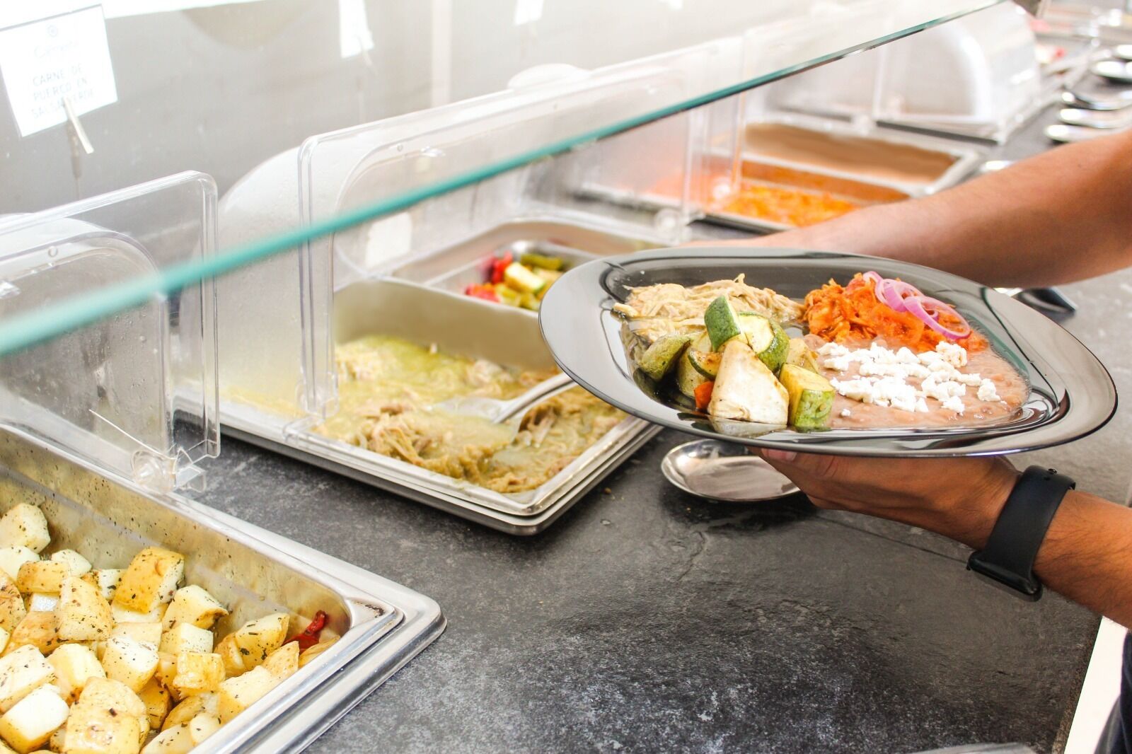 A buffet with various food items including potatoes, shredded chicken, and vegetables.