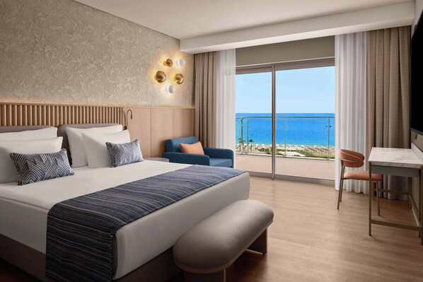 A modern hotel room with a large bed, a desk, and a view of the ocean. - Akra Sorgun Tui Blue Sensatori - All Inclusive (Manavgat)