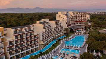 Ein Hotel mit mehreren Etagen, einem zentral gelegenen Schwimmbad und Blick auf die umliegende Landschaft.