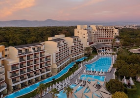 Un hotel con varios pisos, una piscina central y vistas del paisaje circundante.