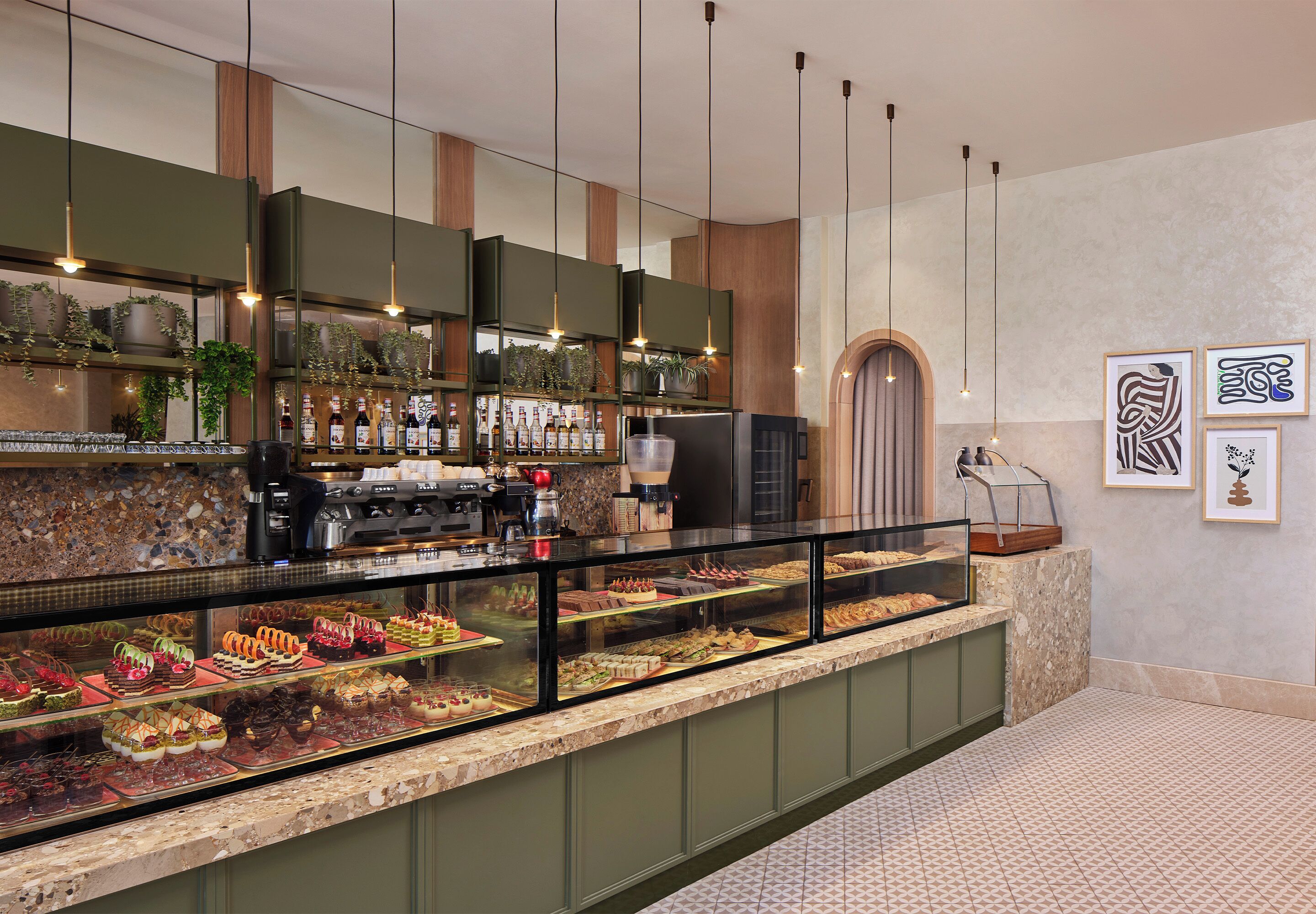 A bakery counter with various pastries and cakes, a coffee machine, and a display case with more baked goods.