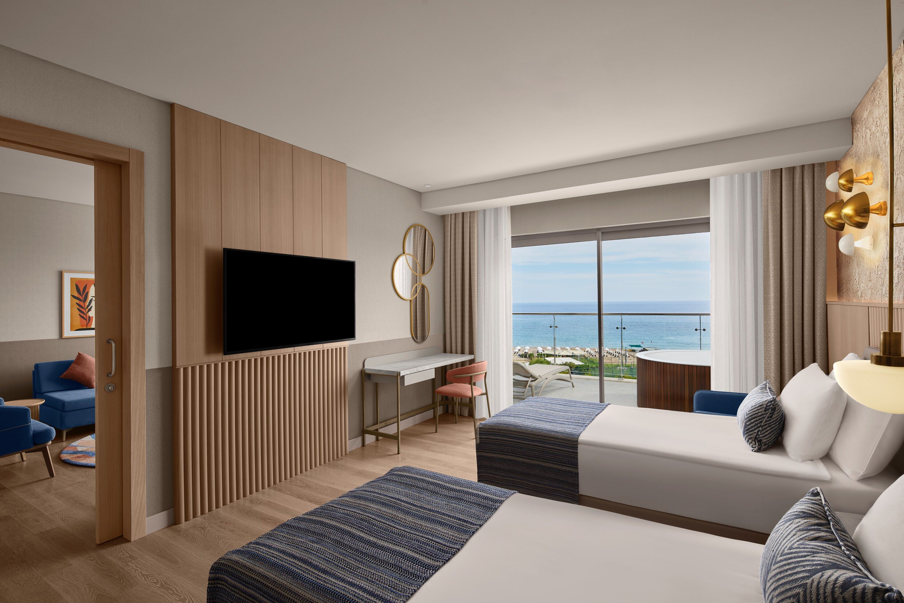 Habitación de hotel con cama, escritorio, televisión y vista al océano.
