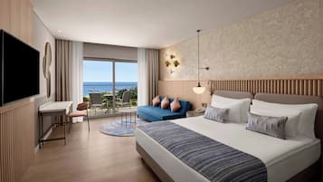 Una habitación de hotel moderna con una cama grande, un escritorio, una silla y un balcón con vistas al mar.