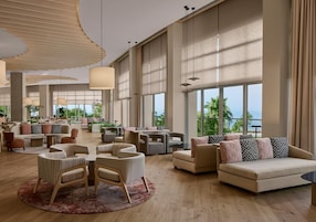 Un hall espacioso con varias zonas de estar, ventanas amplias y vistas al exterior.