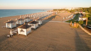 Una spiaggia con file di case bianche sulla riva e ombrelloni, un cielo sereno e un mare calmo.